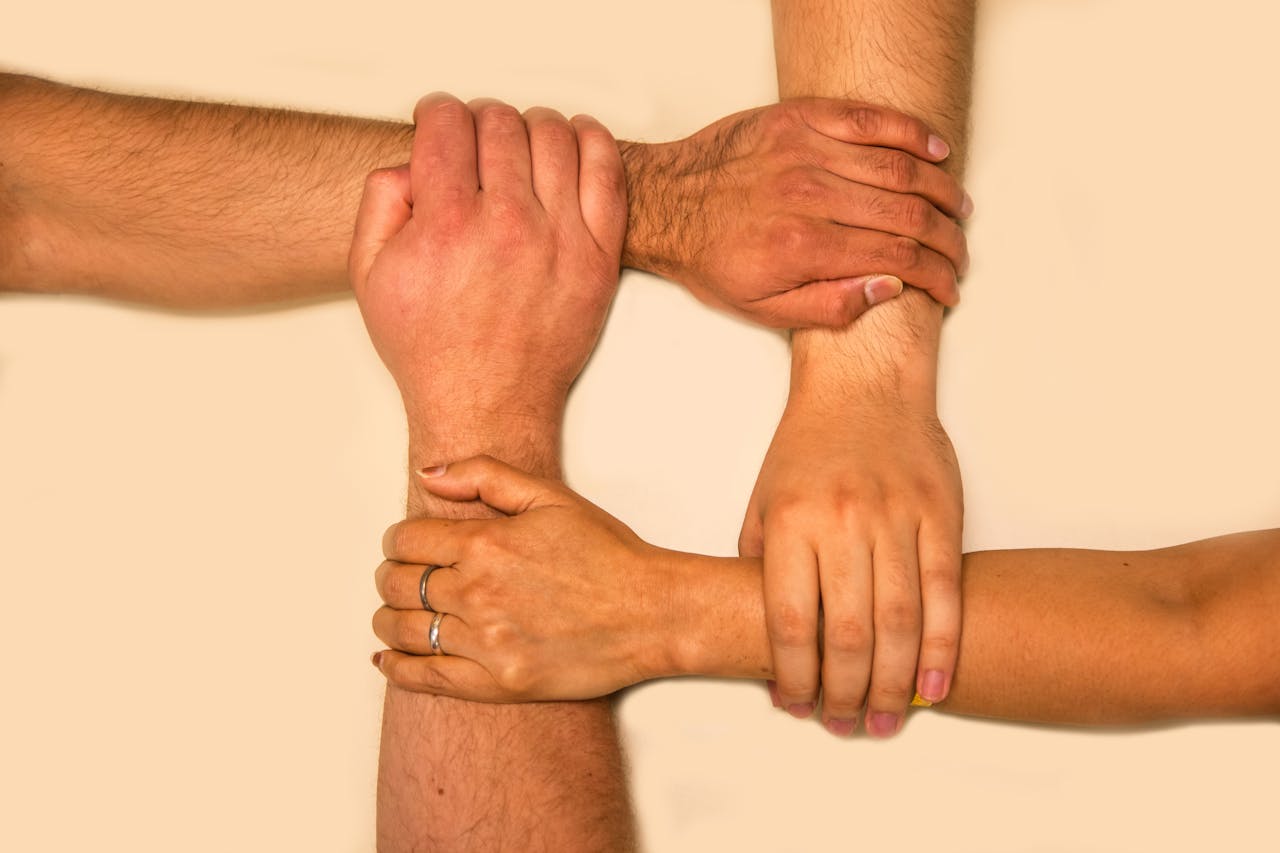 Mastering the First Impression: Your intriguing post title goes here Four hands interlocked, representing unity and teamwork in a symbolic gesture.