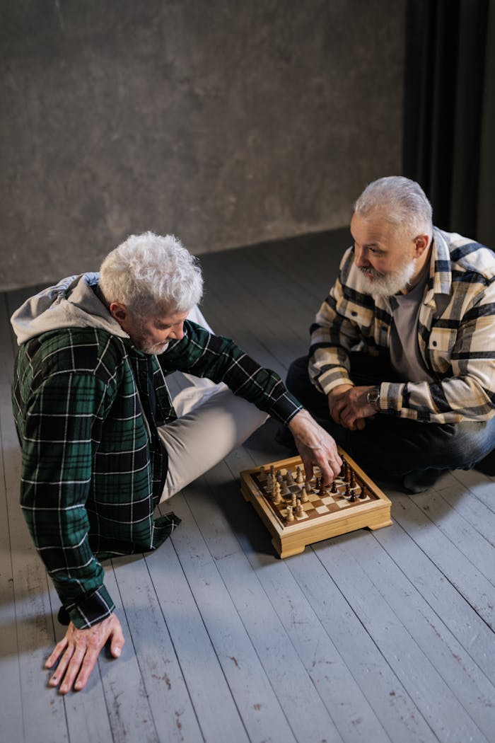 Two senior men playing chess indoors, showcasing positive aging and friendship.