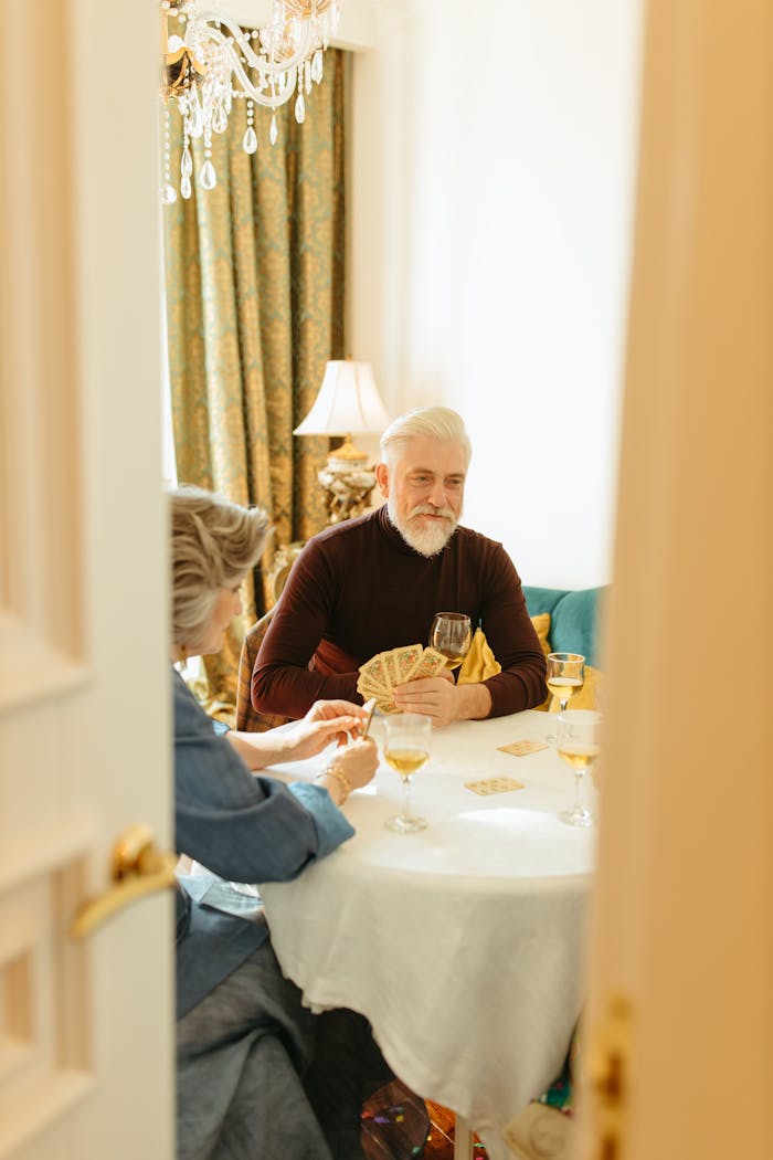 Two senior adults playing cards and enjoying leisure time indoors with a warm atmosphere.
