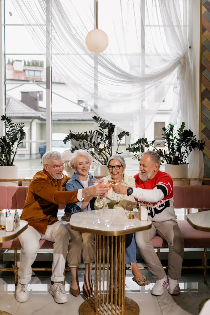 Elderly friends cheer with drinks in a chic café, celebrating togetherness and friendship.